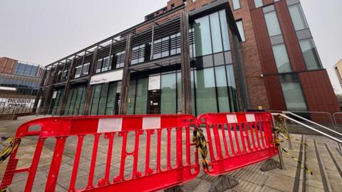 A barrier of temporary fences, secured together with yellow and black tape, outside Durham Passport Office.