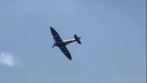 Spitfire aircraft mid-flight in blue sky