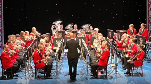 Photo of the Burbage Brass Band performing a concert dressed in red blazers