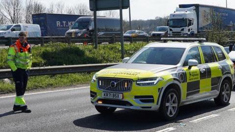 A National Highways car parked on a dual carriageway with heavy traffic on the opposite side of the road