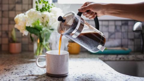 Pouring coffee from a cafetiere into a coffee mug.