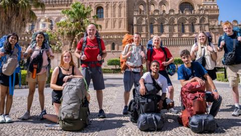 All 10 Race Across the World contestants, pictured outside Palermo Cathedral, lined up and ready to go with their backpacks on
