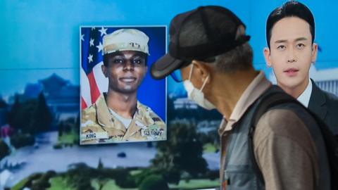 A man walks past a TV in South Korea showing the face of US soldier Travis King