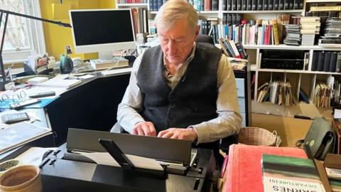 Julian Barnes in his office, typing on an electric typewriter