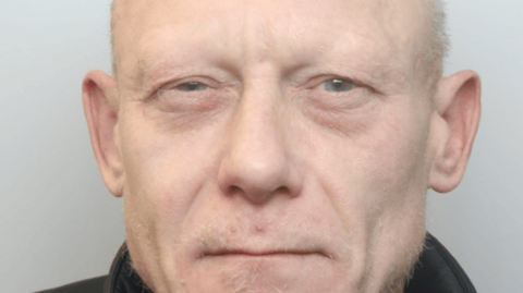 Police photo of Curbishley, he has short blonde hair and wears a black jacket