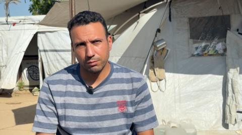 Saber Abu al-Kas sits outside a tent in Gaza
