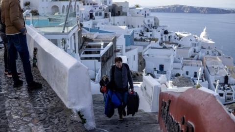 People leaving the Port of Fira carrying a suitcase 