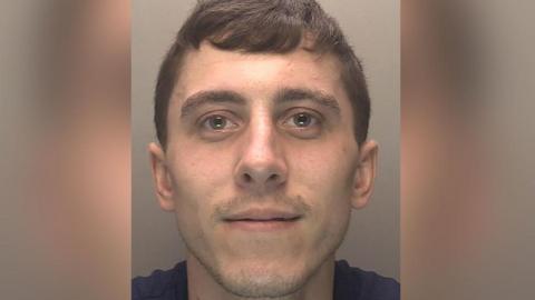Police custody image of Stephen Grzyb who has short brown hair and is wearing a navy t-shirt.