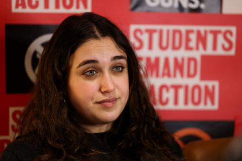 Brown University student Mia Tretta sat in front of a poster reading 'Students Demand Action'