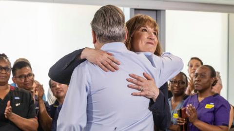 Keir Starmer and Rachel Reeves hug, while NHS staff look and applaud