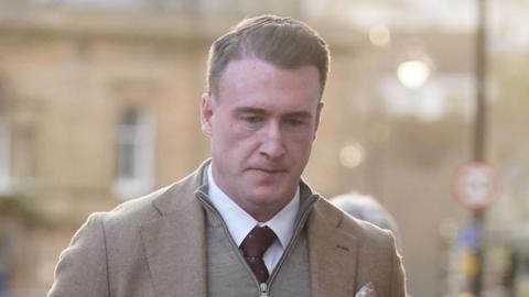 Former Scotland rugby captain Stuart Hogg in a light brown jacket with a grey-zipped top underneath and a purple tie. 