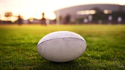Closeup shot of a white rugby ball placed on grass in a field