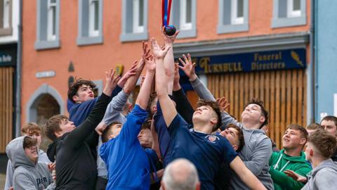 A group of young men fight over a small leather ball on the streets of Jedburgh
