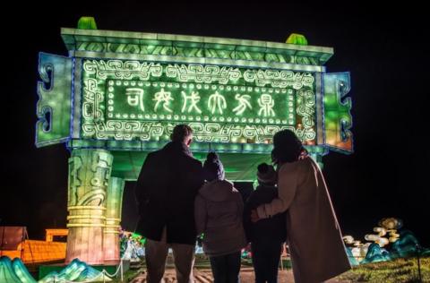 A group pf people look up at a giant green illumination as part of the Longleat Festival of Light