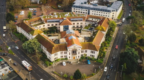 A bird's eye view of the Poole Civic Centre, a two-storey art deco building bordered by roads either side of it.