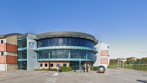 An external view of the curved entrance to Redcar and Cleveland College. The second and third storey are glass fronted.