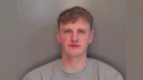 Matthew Hindhaugh with short brown hair looking at camera wearing a grey jumper.