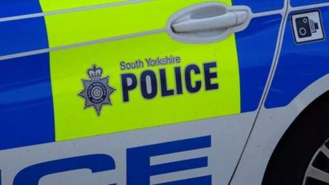 The rear door nearside panel of a police car with the South Yorkshire Police logo