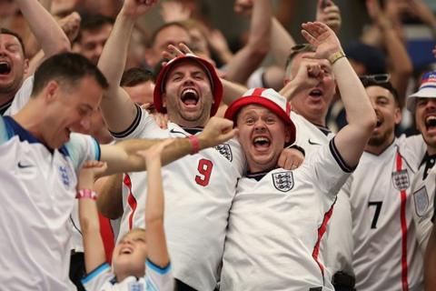 Men in England tops singing and cheering