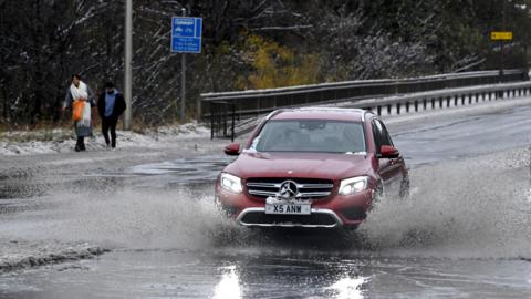 A car drives through water along the A90, as a result of Storm Bert, in Cramond near Edinburgh