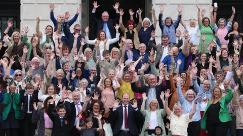 Communities minister Gordon Lyons (centre front) with campaigners from the deaf community at a rally outside the Parliament Buildings at Stormont.