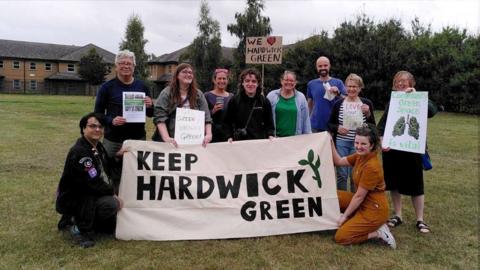 A group of people standing with placards calling to save hardwick green