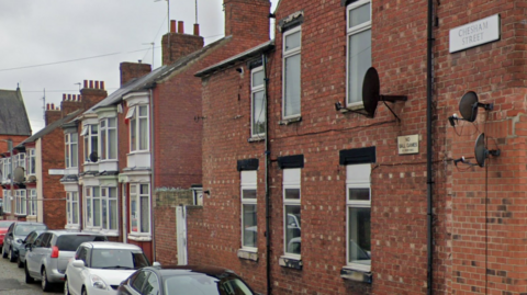 A terraced street of houses. To the top left of the picture is a street sign reading Chesham Street above some satellite discs.