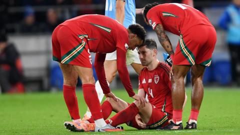 Ben Davies shows his distress at being injured as team-mates gather round