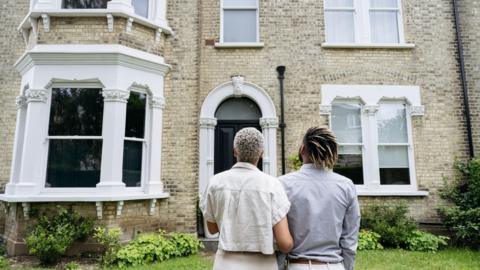 A couple look towards a Victorian property from outside 