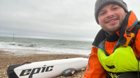 Mike Lambert on the beach, next to a kayak