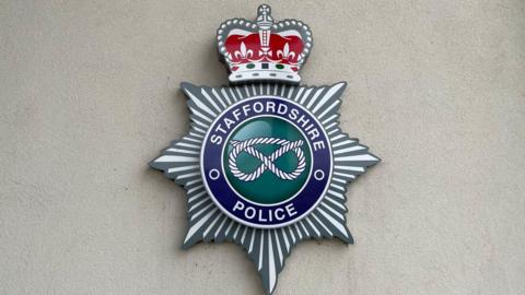 A large crest on a wall, with the words Staffordshire Police around the edge, and an image of a knot in the middle