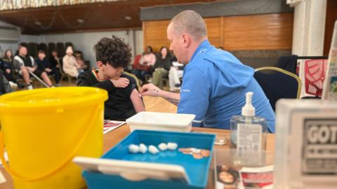 Vaccination clinic with someone receiving an injection