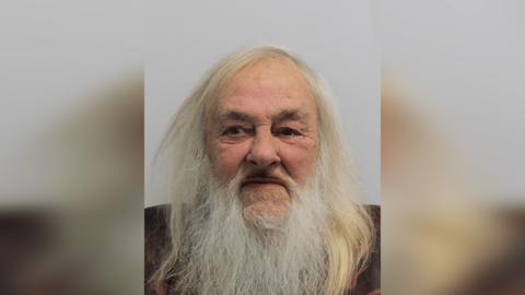 A custody image of David Cheneler. He has long white hair and a white beard.
