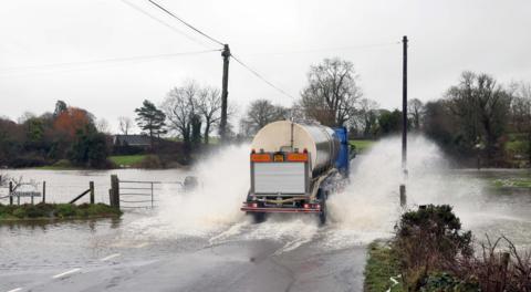 A truck driving through a flooded road. 