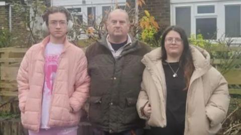 Jason Ebury stood alongside his kids outside their home