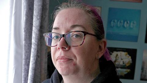 Emma wears glasses and a black hoodie.