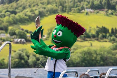 Clyde the Scotland team mascot rides a RIB boat with the baton during the Queen's Baton Relay