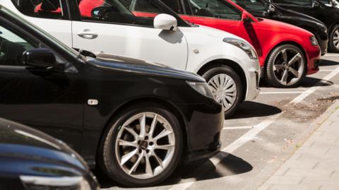 Several cars parking diagonally, side by side in parking bays.