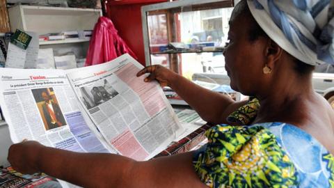 A woman reads a local newspaper 'L'Union' announcing the death of Gabon's President Omar Bongo Ondimba in a shop in Libreville on June 9, 2009.