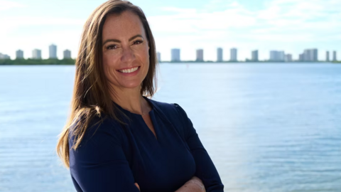 Emily Gregory, the Democratic nominee for Florida state house district 87, stands in front of a waterway with buildings in the background.