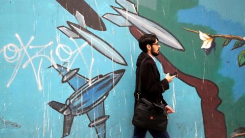Man walks past mural on the wall of the former U.S. Embassy in Tehran, Iran, on May 9, 2018