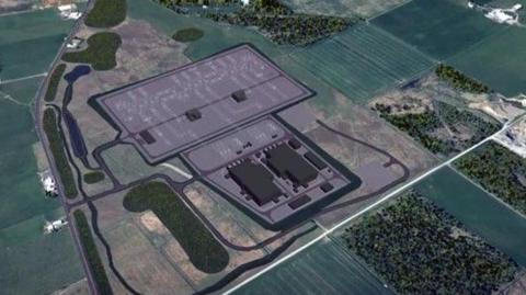 An aerial shot showing a grey area with green fields surrounding.