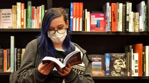 A customer reads a book in a Watersones store