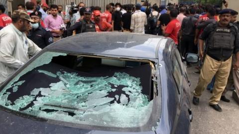 A plainclothes police officer (L) surveys the site of an attack at the Pakistan Stocks Exchange entrance in Karachi June 29, 2020.