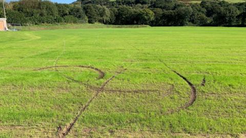 Football pitch with deep tyre tracks running through it