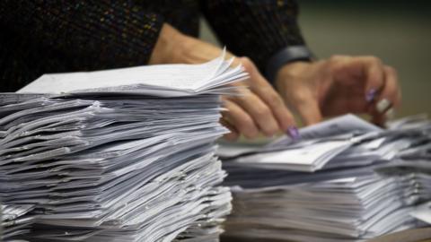 Woman's hands counting stacks of ballot papers