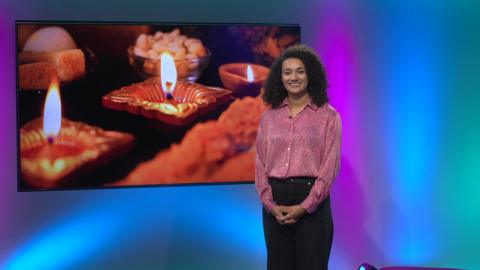 Nina in the Newsround studio with candles in the screen