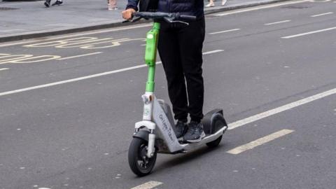 A green and grey e scooter on a road 