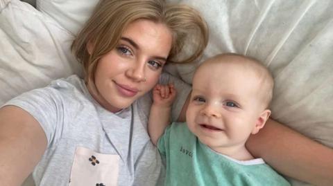 Ellie Howells pictured with son Teddy. She is wearing a white t-shirt and Teddy is in a green baby grow. 