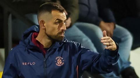 Alex Lawless sends out messages and directions to the players during Luton's game against Cambridge